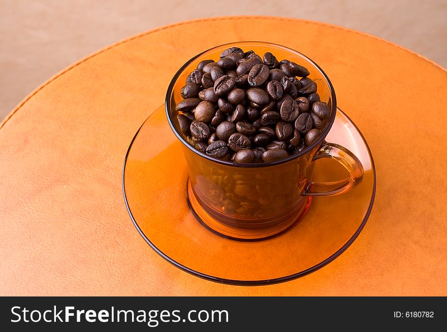 A cup with coffee beans on a table. A cup with coffee beans on a table