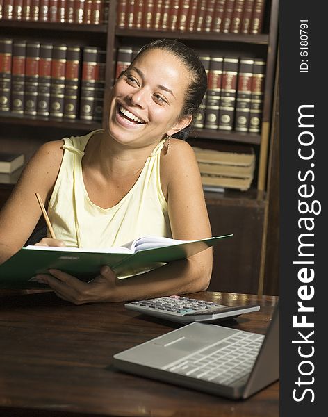 Woman laughing while she reads a book in a library. Vertically framed photo. Woman laughing while she reads a book in a library. Vertically framed photo.