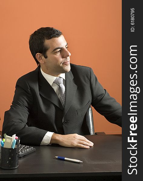 Businessman seated at desk looking off into the distance. Vertically framed photo. Businessman seated at desk looking off into the distance. Vertically framed photo.