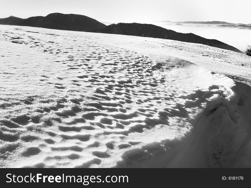 The large flat snow area in the mountains with interesting snow texture in balack and white. The large flat snow area in the mountains with interesting snow texture in balack and white