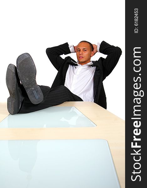 A young satisfied businessman sitting by desk at office feet on table thinking. A young satisfied businessman sitting by desk at office feet on table thinking.