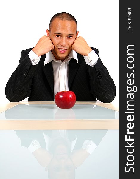 Young businessman sitting in front of a red apple thinking and smiling. Isolate over white. Young businessman sitting in front of a red apple thinking and smiling. Isolate over white.