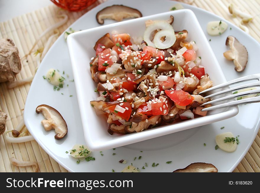 A salad of mushrooms and tomatoes with sesame seeds