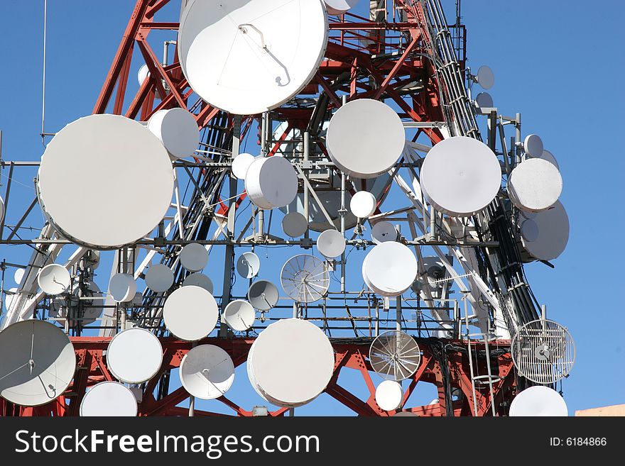 Lots of satellite dishes on a big antenna. Lots of satellite dishes on a big antenna