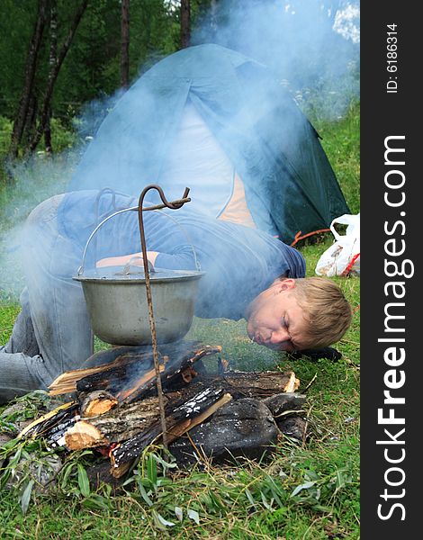 Image of the guy planting a fire and tent on the nature. Image of the guy planting a fire and tent on the nature