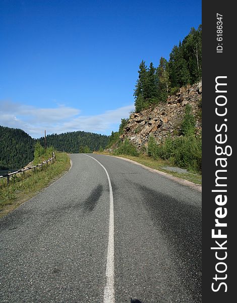 Road going near a rock under the blue sky. Road going near a rock under the blue sky