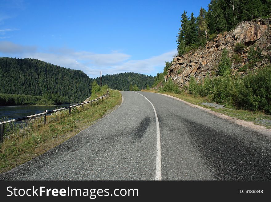 Road going near a rock under the blue sky. Road going near a rock under the blue sky