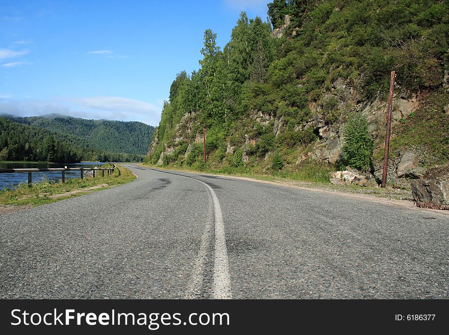 Road going near a rock under the blue sky. Road going near a rock under the blue sky