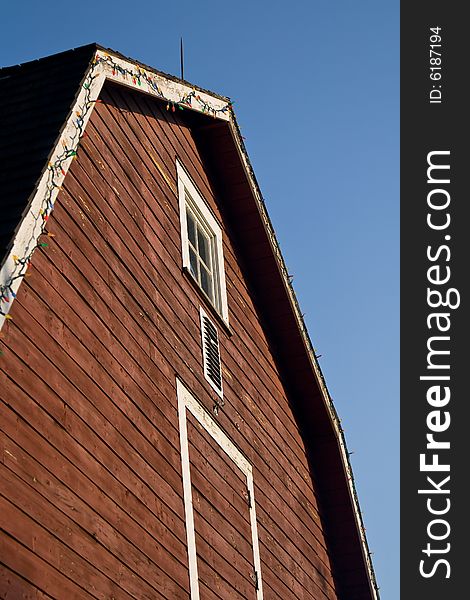 An older red barn facing a sunset, decorated with Christmas Lights along the edge of the roof. An older red barn facing a sunset, decorated with Christmas Lights along the edge of the roof.