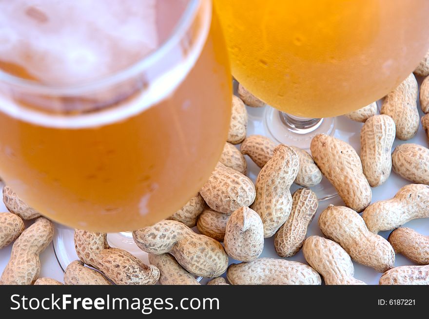 Beer in glass  and peanuts  in shells.