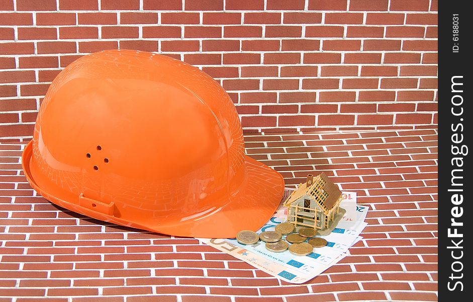 Hardhat with euro banknotes and model house on brick background. Hardhat with euro banknotes and model house on brick background
