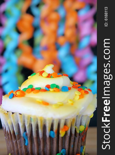 One cupcake with sprinkles and ribbons hanging in the background. Used a shallow depth of field and selective focus on the middle part of cupcake and sprinkles.