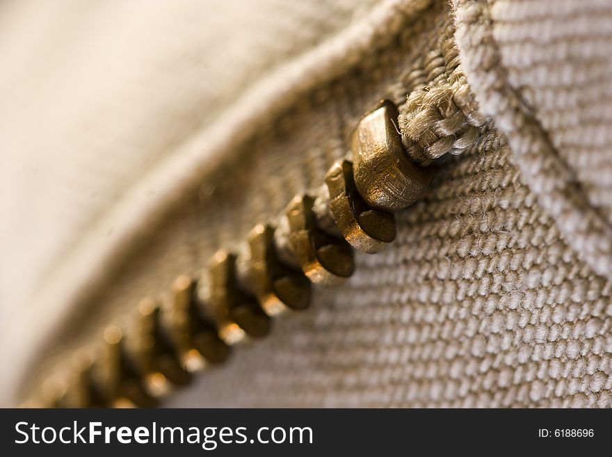 Close-up shot of one part of a copper coloured pants zipper. Close-up shot of one part of a copper coloured pants zipper