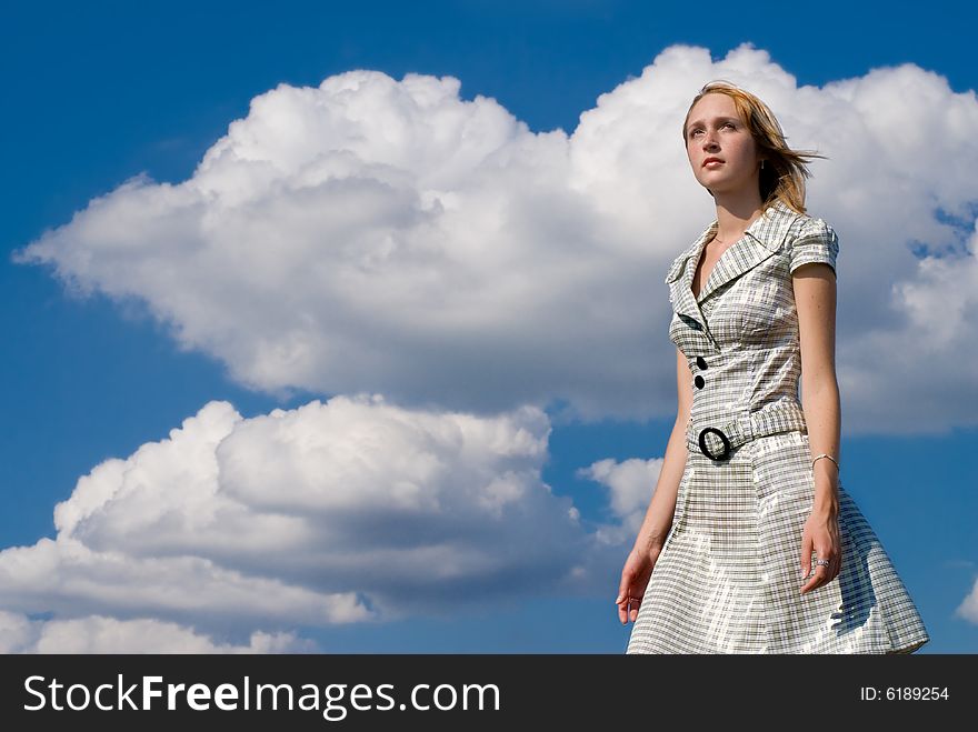 Girl on a background big clouds inthe blue sky. Girl on a background big clouds inthe blue sky