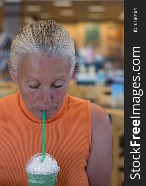 Senior woman drinking cold beverage in bookstore. Senior woman drinking cold beverage in bookstore