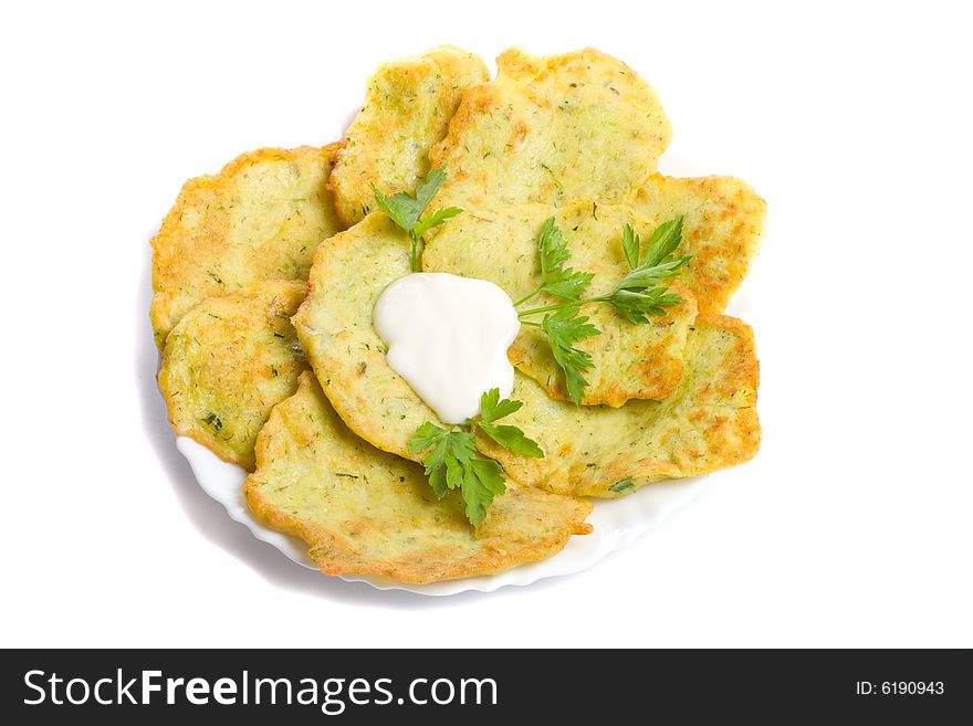 Close-up pancake from marrow with parsley on plate, isolated over white background