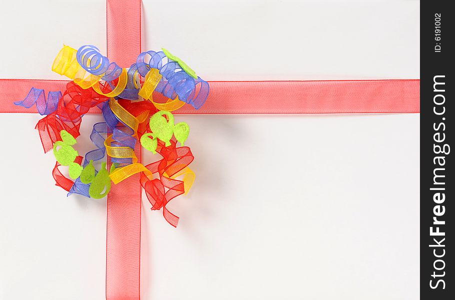 White gift box with red ribbon and yellow, blue, red bow