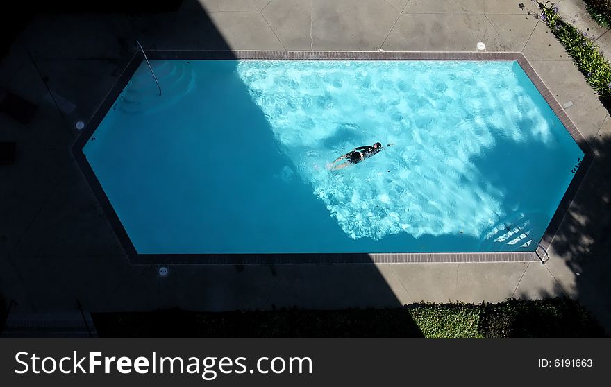 Aerial View of Male Swimmer in Shadowed Swimming Pool. Aerial View of Male Swimmer in Shadowed Swimming Pool