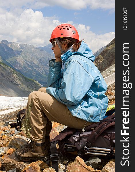Mountaineer girl sitting on backpack and looking to mountains. Mountaineer girl sitting on backpack and looking to mountains