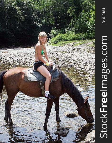 Beautiful making look younger girl sits in saddle on on walk in mountain. Beautiful making look younger girl sits in saddle on on walk in mountain