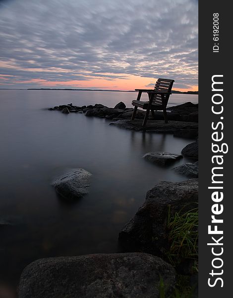 Sunset by the lake with empty chair, long exposure