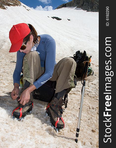 Climber girl wearing the crampon on snow hill of mountain