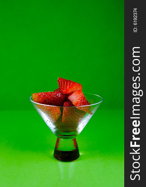 Strawberries in a cocktail glass islolated against a green background. Strawberries in a cocktail glass islolated against a green background