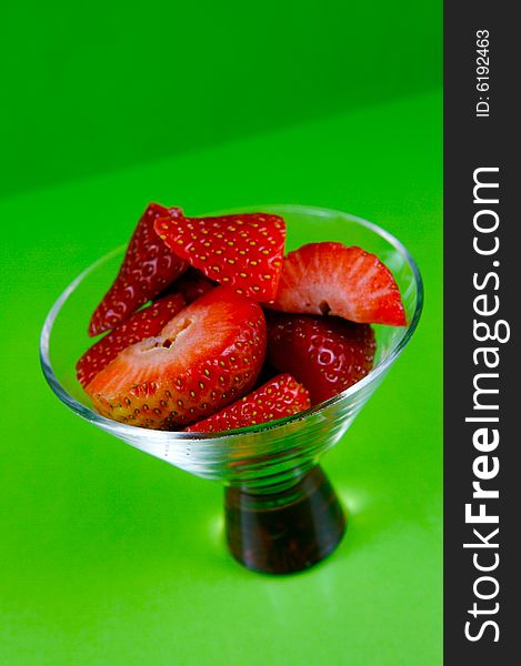 Strawberries in a cocktail glass islolated against a green background. Strawberries in a cocktail glass islolated against a green background