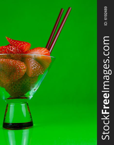 Strawberries in a cocktail glass islolated against a green background. Strawberries in a cocktail glass islolated against a green background