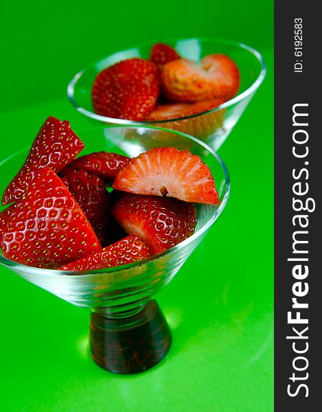 Strawberries in a cocktail glass islolated against a green background. Strawberries in a cocktail glass islolated against a green background