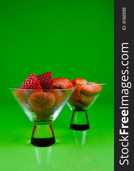 Strawberries in a cocktail glass islolated against a green background. Strawberries in a cocktail glass islolated against a green background