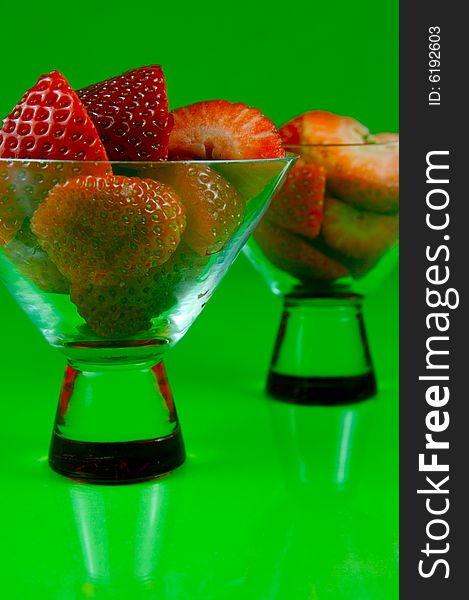 Strawberries in a cocktail glass islolated against a green background. Strawberries in a cocktail glass islolated against a green background