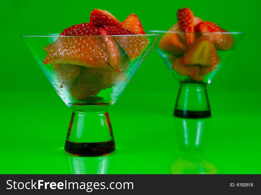 Strawberries in a cocktail glass islolated against a green background. Strawberries in a cocktail glass islolated against a green background