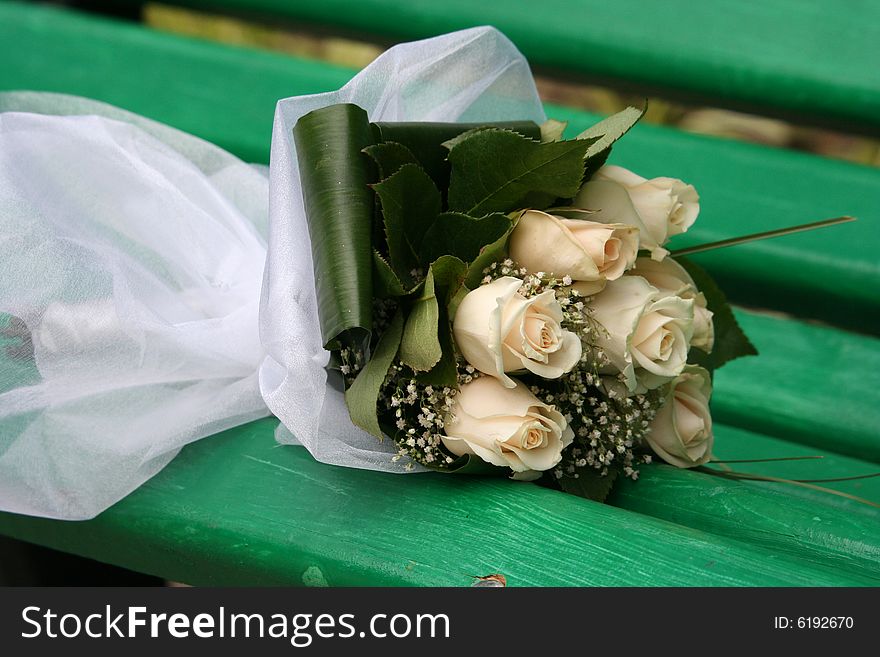 The wedding bouquet lays on a bench in park. The wedding bouquet lays on a bench in park.