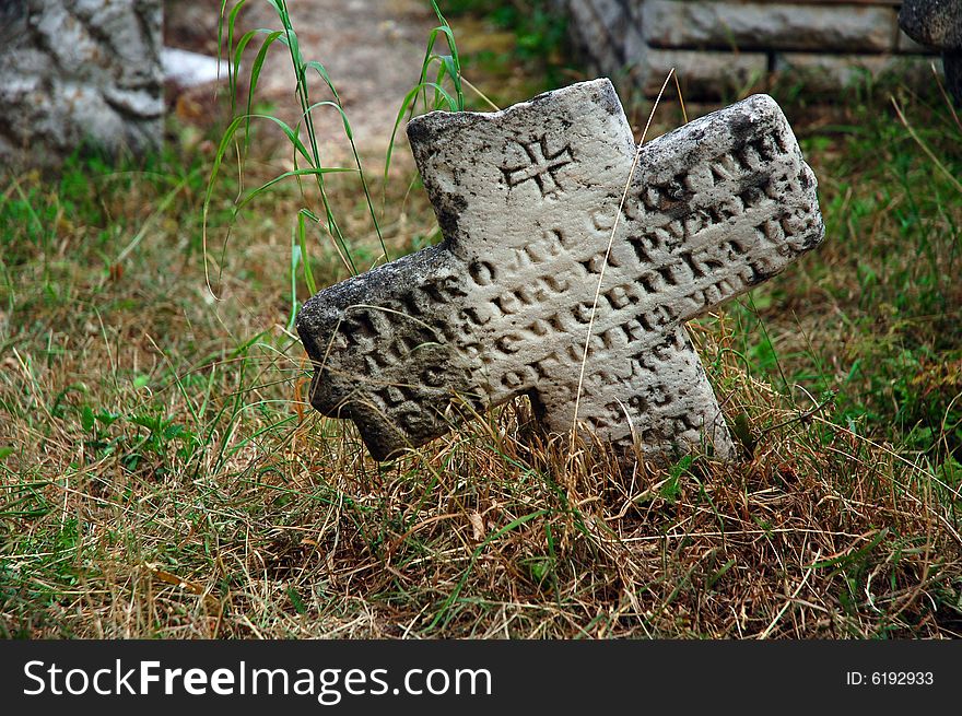 Medieval crooked stone tombstone with undistinguishable writings. Medieval crooked stone tombstone with undistinguishable writings