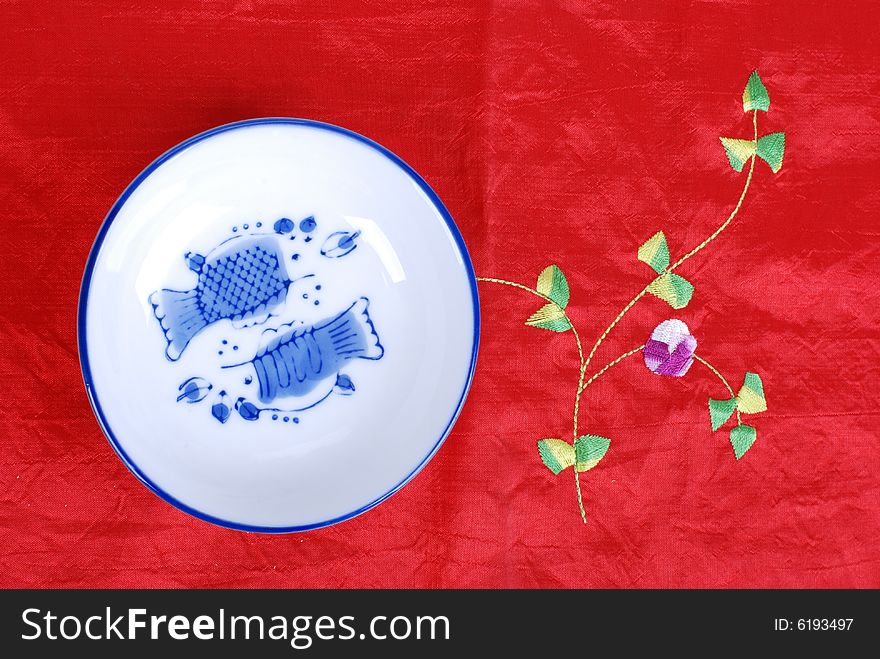 A small dish on a Chinese style table cloth. A small dish on a Chinese style table cloth