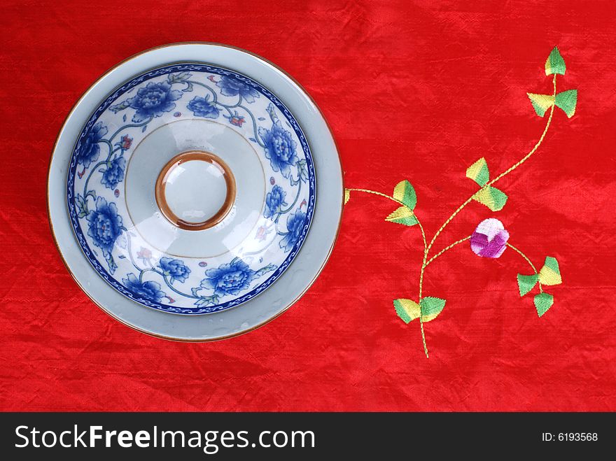 A tea cup on a Chinese style table cloth. A tea cup on a Chinese style table cloth