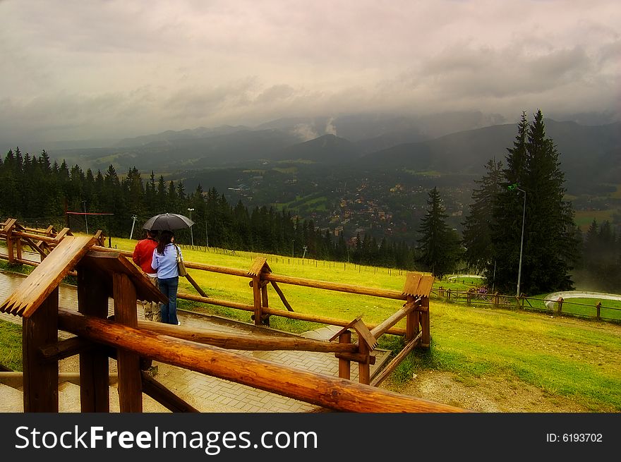 Young couple is looking on Zakopane from mountain in the rain. Young couple is looking on Zakopane from mountain in the rain