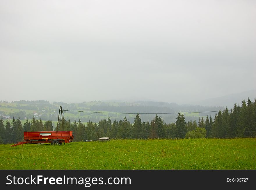 Red trailer on the foggy green hill. Red trailer on the foggy green hill