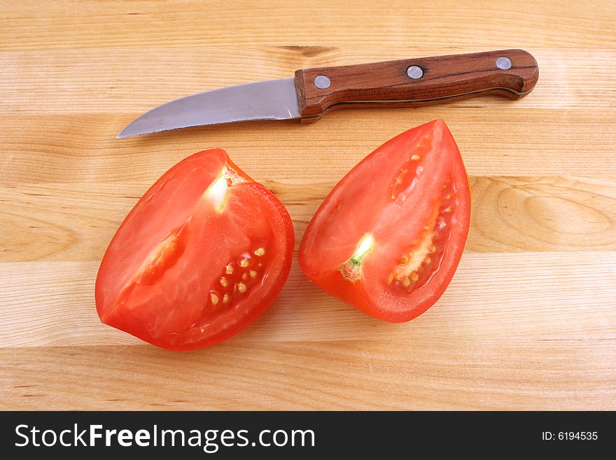 Fresh tomato with knife on kitchen board