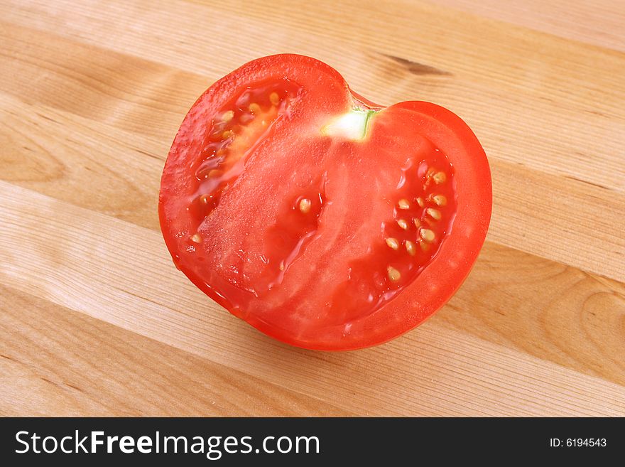 Tomato on wooden kitchen board