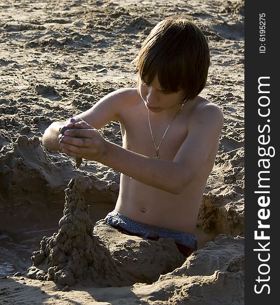 Young boy building sand scultures while sitting in mud hole. Young boy building sand scultures while sitting in mud hole