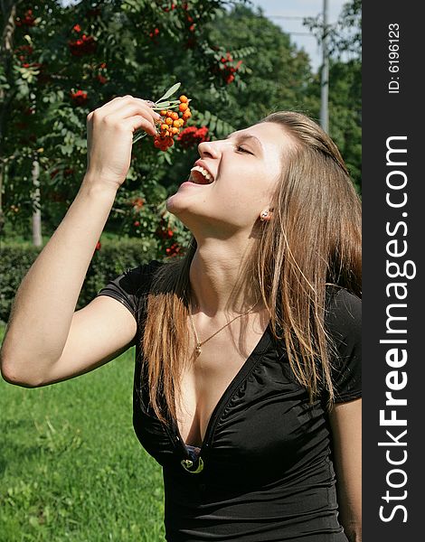 The joyful girl with a branch of a mountain ash in park