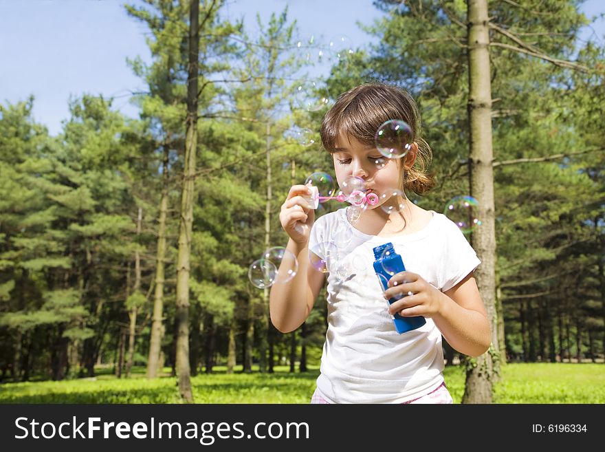 Young girl blowing bubbles in park. Copy space. Young girl blowing bubbles in park. Copy space