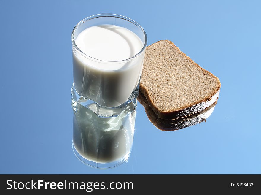 Glass of milk and rye-bread lying on blue sky background. Glass of milk and rye-bread lying on blue sky background