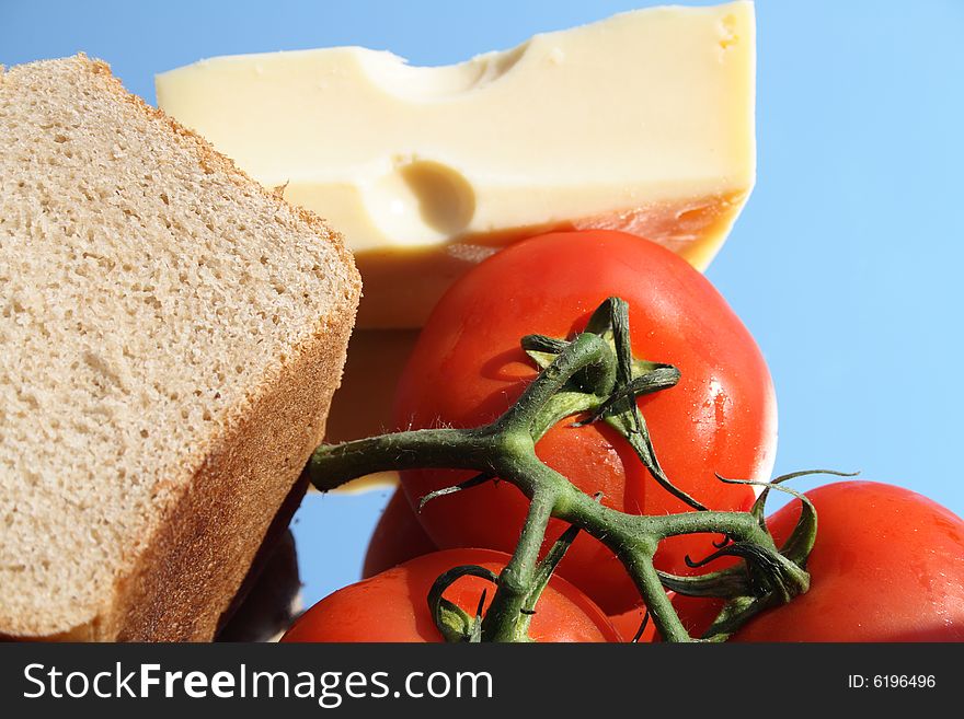 Rye-bread, tomatoes and cheese on blue background. Rye-bread, tomatoes and cheese on blue background
