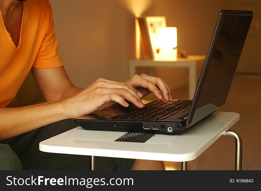 Guy working on his laptop at homein the evening. Guy working on his laptop at homein the evening