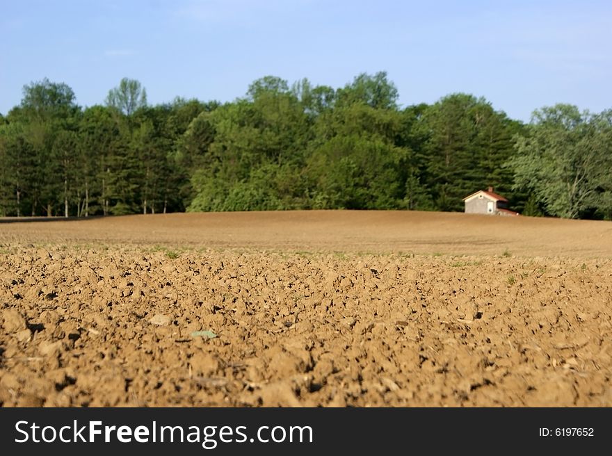 Focus on farmer's field with out of focus farmhouse in background. Focus on farmer's field with out of focus farmhouse in background.