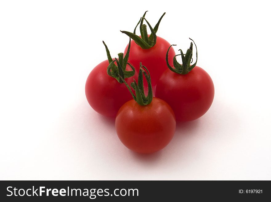 Four cherry tomatoes set against a white backdrop. Four cherry tomatoes set against a white backdrop