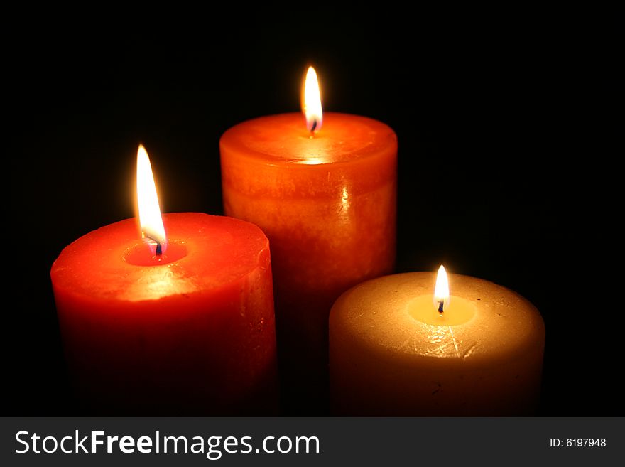 Three candles burning with a black back ground. Three candles burning with a black back ground.